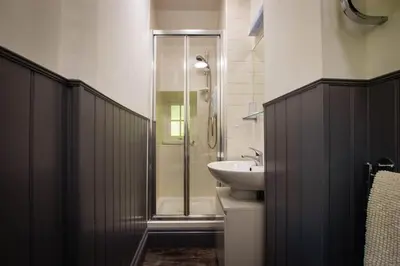 a bathroom with a glass shower and a sink at Noddfa Country House in Harlech