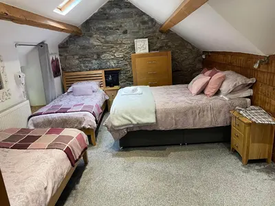a bedroom with two beds and a stone wall at Noddfa Country House in Harlech