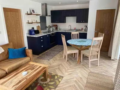 a kitchen and living room with a table and a couch at Serene Llanbedr Retreat with Garden View in Llanbedr