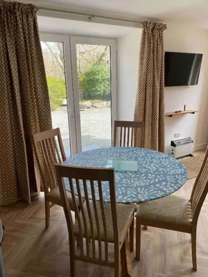 a dining room with a table and chairs and a television at Serene Llanbedr Retreat with Garden View in Llanbedr