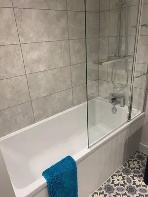 a bathroom with a shower and a tub with a blue towel at Serene Llanbedr Retreat with Garden View in Llanbedr