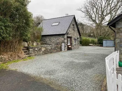 a stone house with a white fence and a driveway at Serene Llanbedr Retreat with Garden View in Llanbedr