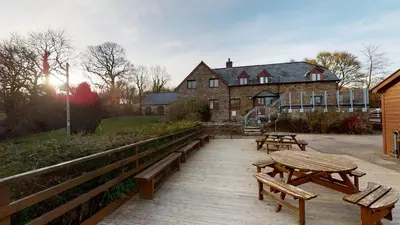 a group of picnic tables and benches on a wooden deck at Traditional Welsh Longbarn in Aber-Brân