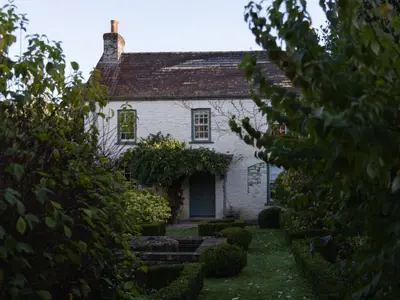 an old white house with a garden in front of it at West Cottage in Llandovery
