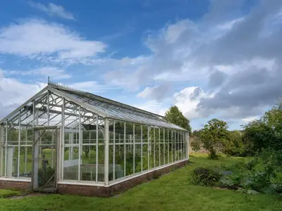 a greenhouse in a garden on a lawn at West Cottage in Llandovery