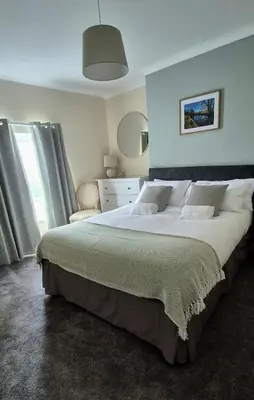 a bedroom with a large bed and a large window at Amaryllis Escapes in Brecon
