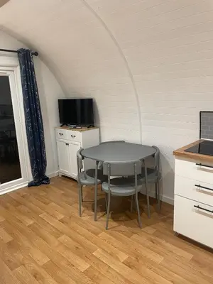 a table and chairs in a room with a tv at AfonCoed - A cozy, quiet stay by the river in Llanrhaeadr-ym-Mochnant