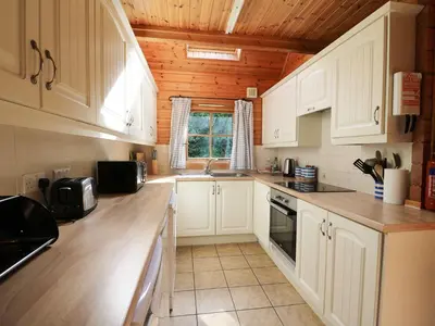 a kitchen with white cabinets and a wooden ceiling at Pen Y Clawdd in Presteigne