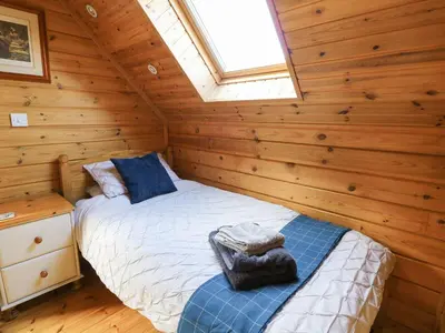 a bedroom with two beds in a log cabin at Pen Y Clawdd in Presteigne