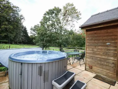 a hot tub in a backyard with a table at Pen Y Clawdd in Presteigne