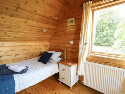a bedroom with a bed in a log cabin at Pen Y Clawdd in Presteigne