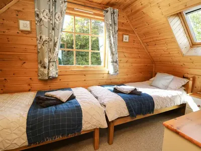 two beds in a log cabin with a window at Dan Y Coed in Presteigne