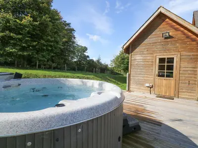 a hot tub on a deck next to a building at Dan Y Coed in Presteigne