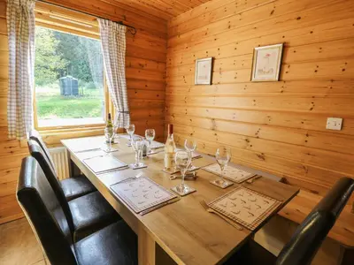 a wooden dining room with a table with wine glasses at Dan Y Coed in Presteigne