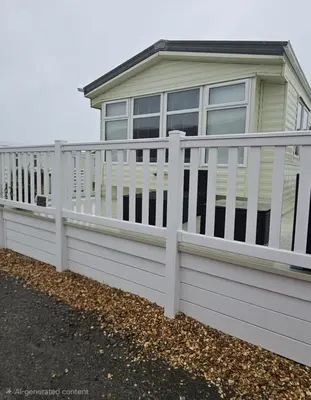 a white vinyl fence in front of a house at The Dancing Dolphin, 124 Aber Bay Holiday Park, Clarach, Aberystwyth in Aberystwyth