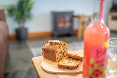 a cutting board with bread and a bottle of drink at Beudy-Talsarnau in Talsarnau