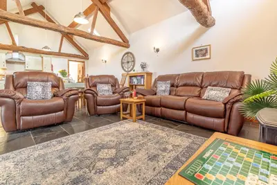 a living room with leather furniture and a table at Beudy-Talsarnau in Talsarnau