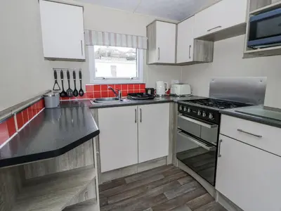 a kitchen with white cabinets and a stove top oven at Brynowen Holiday Park - 22432 in Borth