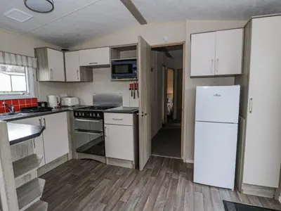 a kitchen with white cabinets and a white refrigerator at Brynowen Holiday Park - 22432 in Borth