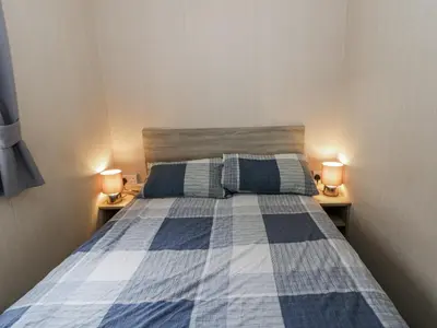 a bedroom with a blue and white bed with two lamps at Brynowen Holiday Park - 22432 in Borth