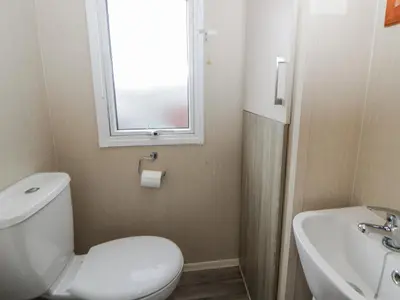 a bathroom with a toilet and a sink and a window at Brynowen Holiday Park - 22432 in Borth