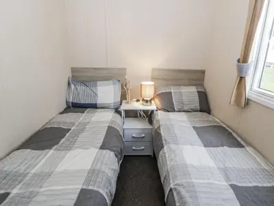 two twin beds in a small room with a table at Brynowen Holiday Park - 22432 in Borth