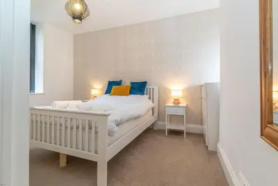 a bedroom with a white bed with blue pillows at Hafan-Glan-Mor in Barmouth