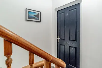 a black door on a white wall next to a staircase at Hafan-Glan-Mor in Barmouth