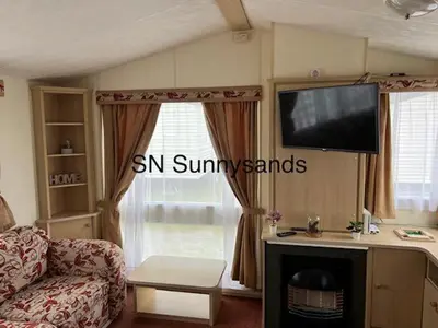 a living room with a couch and a tv at Lyons Sunnysands - Sandy Cove 50 in Llanddwywe