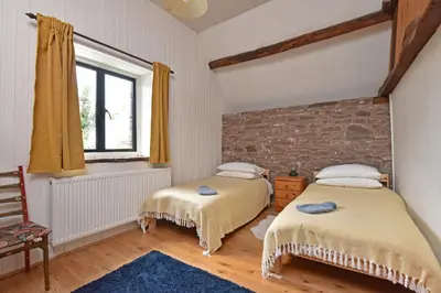 two beds in a room with a brick wall at The Hayloft at Cwmffrwd Farm in Cathedine