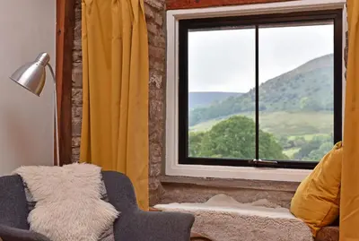 a room with a chair and a window with a view at The Hayloft at Cwmffrwd Farm in Cathedine