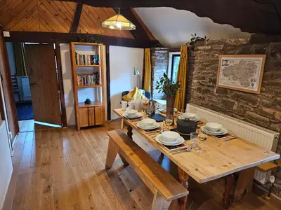 a dining room with a wooden table and a stone wall at The Hayloft at Cwmffrwd Farm in Cathedine