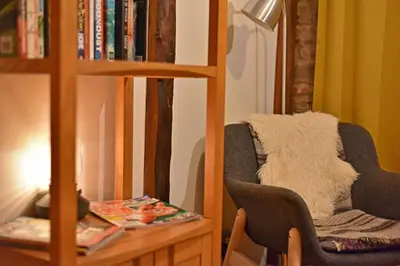 a living room with a chair and a book shelf at The Hayloft at Cwmffrwd Farm in Cathedine