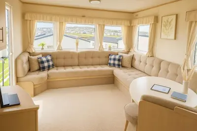 a living room with a large couch and windows at Welsh Seaview Stay 3 bed caravan by pool, club and beach in Aberystwyth