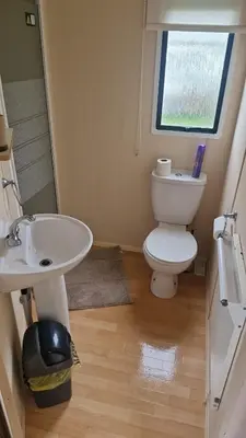 a bathroom with a toilet and a sink and a window at Welsh Seaview Stay 3 bed caravan by pool, club and beach in Aberystwyth
