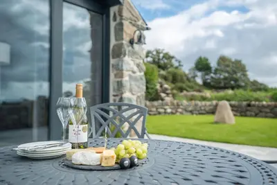 a table with a plate of grapes and a bottle of wine at Y-Ddol in Dyffryn