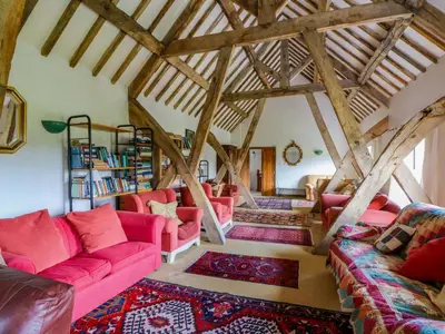 a living room with pink furniture and wooden beams at Gaer Hall in Welshpool