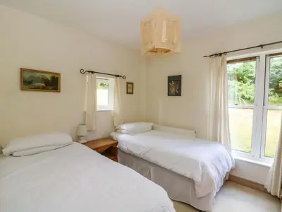 two beds in a room with a window at Gaer Hall in Welshpool