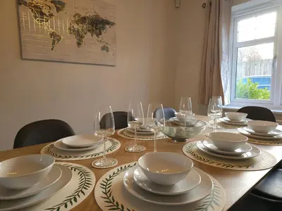 a wooden table with plates and bowls and wine glasses at STYLISH & SPACIOUS 4 BEDROOM HOUSE - FREE DRIVEWAY PARKiNG in Shrewsbury