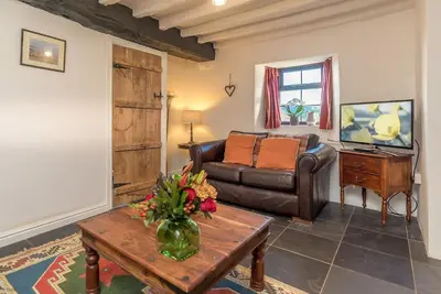 a living room with a leather couch and a table at Y-Felin in Dyffryn