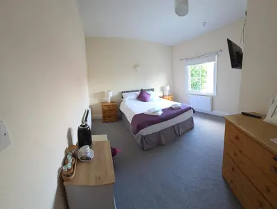 a bedroom with a bed with purple sheets and a window at The Stokesay Inn in Craven Arms