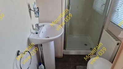 a bathroom with a sink and a shower and a toilet at Mountain view 039 in Barmouth