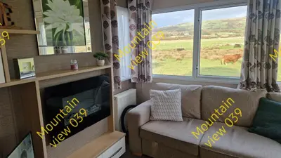 a living room with a couch and a tv and a window at Mountain view 039 in Barmouth