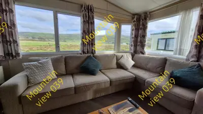 a couch sitting in a living room with windows at Mountain view 039 in Barmouth