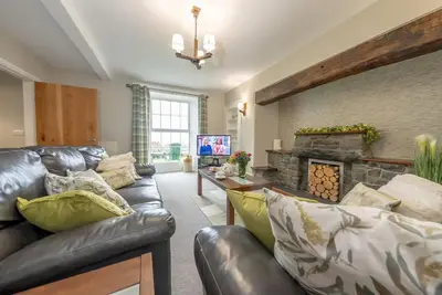 a living room with a leather couch and a fireplace at Faeldre in Dyffryn