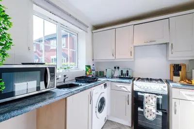 a kitchen with white cabinets and a sink and a microwave at Long Term Stay 3 Bed 1 Bath & Parking Shropshire in Oswestry