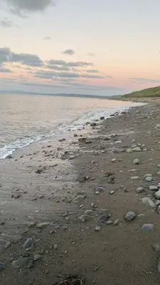 a beach with rocks on the sand and the water at Manteg in Aber-Arth