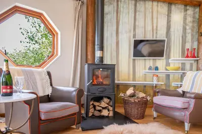 a living room with a wood burning stove at Saffir Luxury Eco Lodge, log-fired bath & views in Dihewid