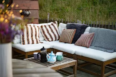 a white couch with pillows on a patio at Saffir Luxury Eco Lodge, log-fired bath & views in Dihewid