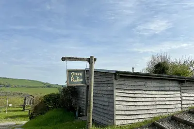 a sign on a pole next to a wall at Saffir Luxury Eco Lodge, log-fired bath & views in Dihewid